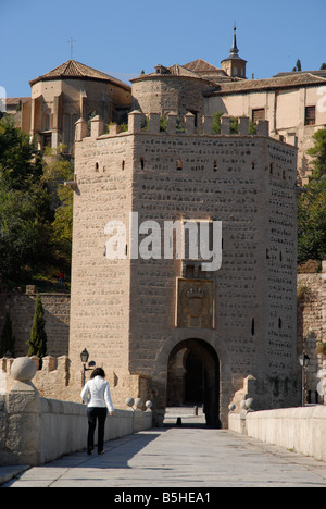 Donna che cammina attraverso il Puente de Alcantara alla città di Toledo, Castilla-la Mancha, in Spagna Foto Stock
