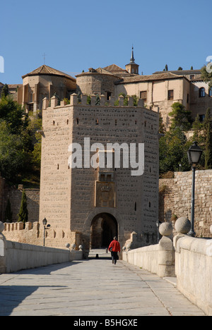 Uomo che cammina attraverso il Puente de Alcantara alla città di Toledo, Castilla-la Mancha, in Spagna Foto Stock