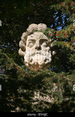 Uno stile antico scultura permanente di testa tra gli alberi nei Giardini Botanici, Victoria Park, bagno, Somerset, Regno Unito Foto Stock