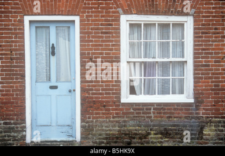 Una volta elegante blu pallido in legno e porte di vetro e sash bianco window set in rosso mattone parete della terrazza casa ora che necessitano di riparazione Foto Stock