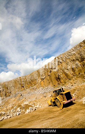 Un immagine angolata di un grande bulldozer lavorando in una cava di estrazione di pietra sotto un cielo blu Foto Stock