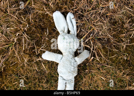 Bambino abbandonato s coniglio giocattolo posa su erba Abstract Foto Stock