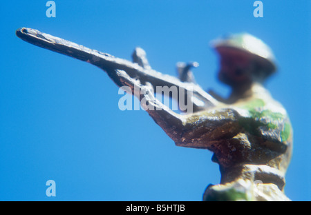 Close up martoriata dipinto di piombo modello in miniatura del soldato in uniforme cachi con tin hat mirando il suo fucile al nemico Foto Stock