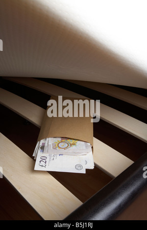 Borra di 20 e 10 sterline Bank of England contanti in una busta ripiene sotto il materasso di un letto Foto Stock