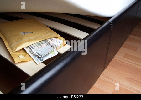 Note della banca nascoste sotto il materasso del letto con la mano