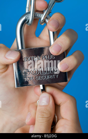 Mani che fissano un lucchetto resistente con la chiave Foto Stock