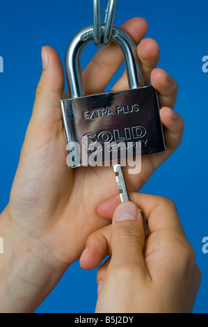 Mani che fissano un lucchetto resistente con la chiave Foto Stock