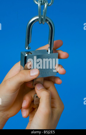 Mani che fissano un lucchetto resistente con la chiave Foto Stock