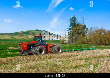 Un trattore gira sulla stoppia in un campo con un aratro di iniziare a preparare il campo per la semina nella regione Palouse di WA Foto Stock