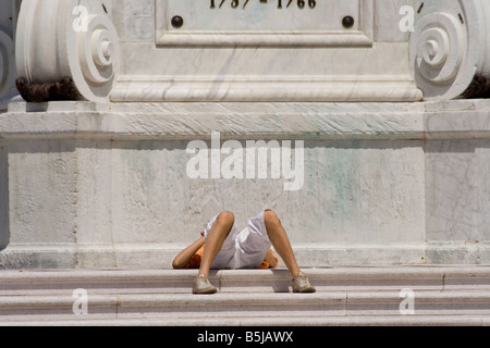 Un uomo disteso dal piedistallo di una statua Foto Stock