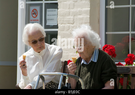 2 Le donne anziane amici seduti seduti insieme a mangiare il gelato coni Foto Stock