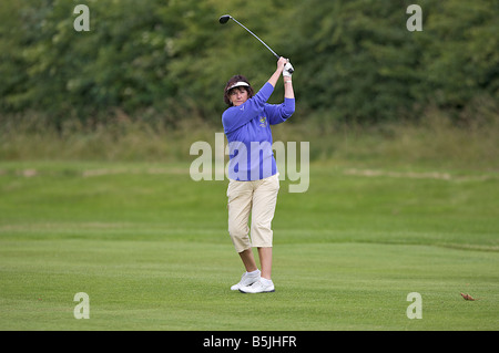 Signora giocando un tiro fuori il fairway Foto Stock