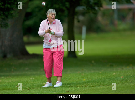 Signora giocando un tiro fuori il fairway Foto Stock