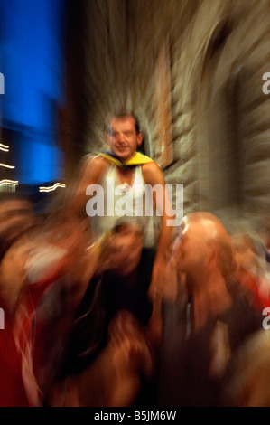 Il fantino vincente è portato aloft dalla sua contrada attraverso le strade di Siena dopo aver vinto il Palio di Siena, Italia Foto Stock