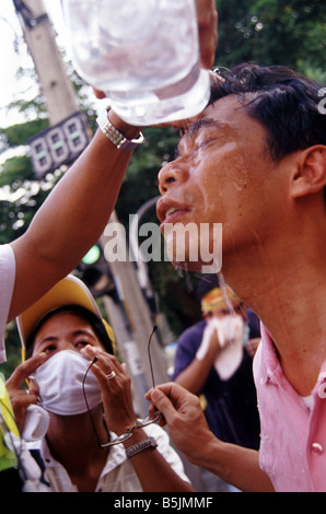 Un Thai anti-government protester ( PAD ) risciacqui il suo viso dopo la polizia ha gettato le scatole metalliche del gas lacrimogeno durante una manifestazione di protesta , Bangkok Foto Stock