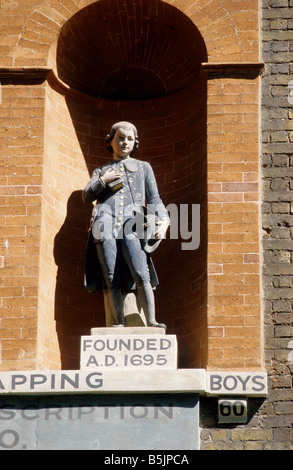 La figura del ragazzo in Coade pietra sopra ingresso alla St John's Old School, Scandrett Street, Wapping, London E1 Foto Stock