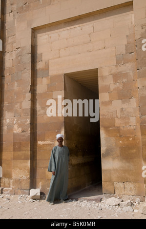 Un nativo del tutore che indossano il tradizionale abito egiziano Galabya in ingresso alla piramide di Saqqara complesso in Egitto Foto Stock