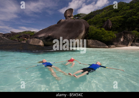 3 bambini flottante per le chiare acque blu di Donald Duck bay nelle Isole Similan Foto Stock