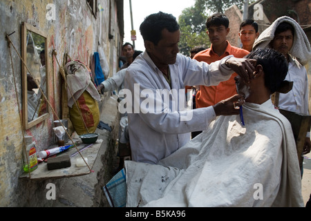 Una rasatura barbiere un client sulla strada nella vecchia Dacca in Bangladesh Foto Stock