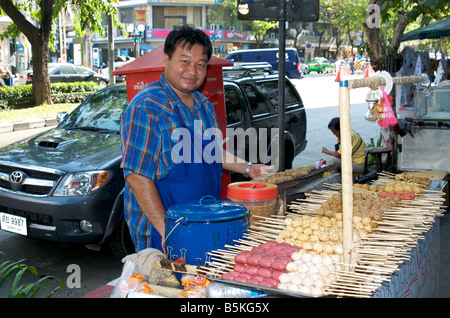 Un sorriso felice polpetta venditore al suo stallo in Silom Road di Bangkok in Thailandia Foto Stock