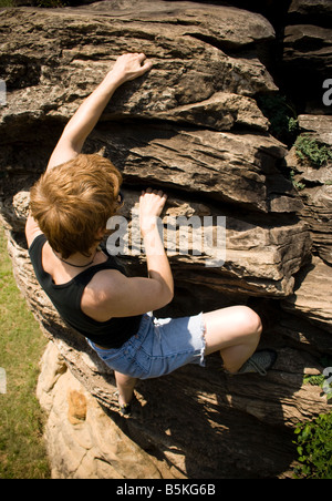 Donna free-climbing una parete di roccia. Foto Stock