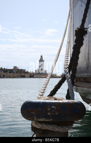 Malaga Costa del Sol Spagna bollard ormeggio con nave la corda allacciate intorno ad esso Malaga faro in background Foto Stock