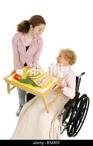 Senior disabili riceve un pasto a casa la consegna da friendly teen volunteer vista verticale isolato su bianco Foto Stock