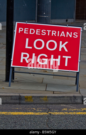 Un 'pedoni guardare a destra' cartello stradale su una strada in pendenza. Foto Stock