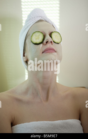 Donna di ottenere un trattamento del viso con cetrioli su i suoi occhi. Foto Stock