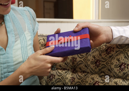 Un uomo che dà un regalo ad una donna. Foto Stock