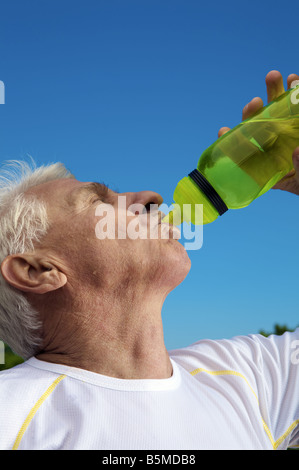 Un uomo anziano di bere dalla bottiglia Foto Stock