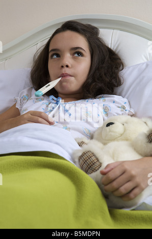 Una bambina a letto per ottenere la sua temperatura presa Foto Stock