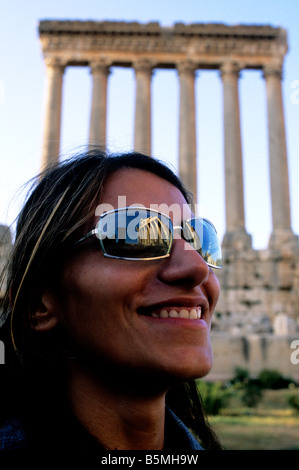 L'imponente facciata del tempio di Bacco si riflette negli occhiali da sole indossati da una donna libanese come lei visita le rovine di Baalbek Foto Stock