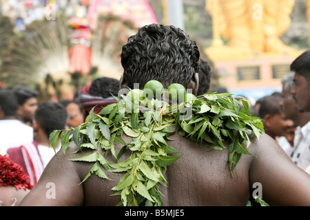 Retro del penitente indiano con foglie di colore verde e i limoni durante il festival di thaipusam, Grotte Batu, Malaysia Foto Stock