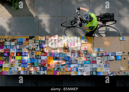 Uomo con bicicletta guardando una tabella di libri presso il South Bank outdoor del mercato del libro, Londra, Inghilterra Foto Stock