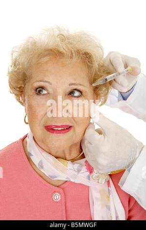 Senior donna ricevere iniezioni cosmetiche per il ringiovanimento del viso Sfondo bianco Foto Stock