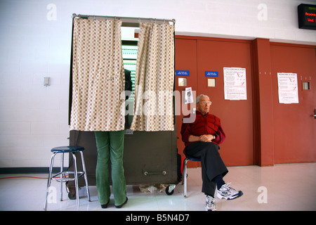 La donna si erge all'interno cabina di voto accanto al polling di attendant, Dobbs Ferry, NY Foto Stock