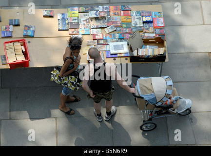 Uomo Donna e bambino in un passeggino guardando una tabella di libri presso il South Bank outdoor del mercato del libro, Londra, Inghilterra Foto Stock