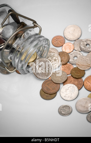 Antico e obsoleto delle monete in euro versato da un contenitore di vetro con sfondo bianco Foto Stock