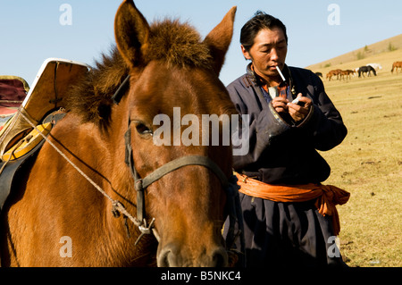 Un nomade mongola gode di una sigaretta nelle vaste praterie della Mongolia. Foto Stock