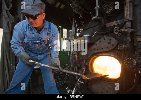 Un vigile del fuoco di badili carbone nella scatola di fuoco di un vapore locomotiva a Durango Silverton Narrow Gauge Railroad Foto Stock