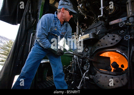 Un vigile del fuoco di badili carbone nella scatola di fuoco di un vapore locomotiva a Durango Silverton Narrow Gauge Railroad Foto Stock