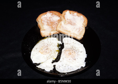 Una coppia di più facile uova con un lato del pane tostato Foto Stock