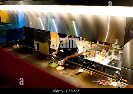 Lo chef cucina in un ristorante di okonomiyaki nel quartiere Shibuya di Tokyo, Giappone. Foto Stock