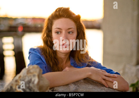 Una giovane donna appoggia le braccia su alcune rocce dal fiume Foto Stock