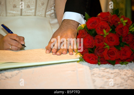 Sposi ha sposato il marito e la moglie tenendo le mani sul registro di matrimonio durante la cerimonia di matrimonio nel Regno Unito Foto Stock