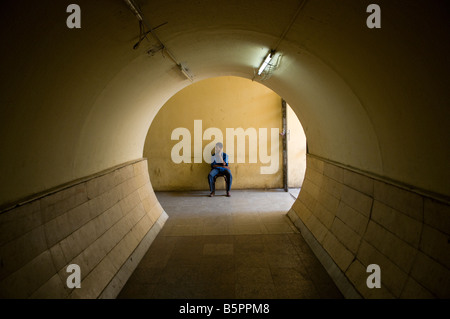 Uomo seduto dentro la zona pedonale di tunnel sotterraneo sotto la strada vicino al Bazaar di Khan El Khalili Cairo Egitto Foto Stock