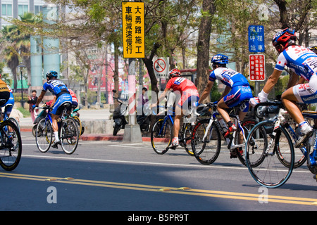 I ciclisti nel peloton ride passato la folla, Tour de Taiwan fase 1 crtierium, Kaohsiung, Taiwan, ROC Foto Stock