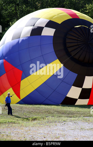 Una mongolfiera in aumento con l'aria calda ed essendo diretta da un uomo di sicurezza Foto Stock