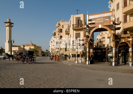 Caleche carro trainato da cavalli passano l'ingresso al bazaar mercato nel centro di Luxor, Egitto Foto Stock